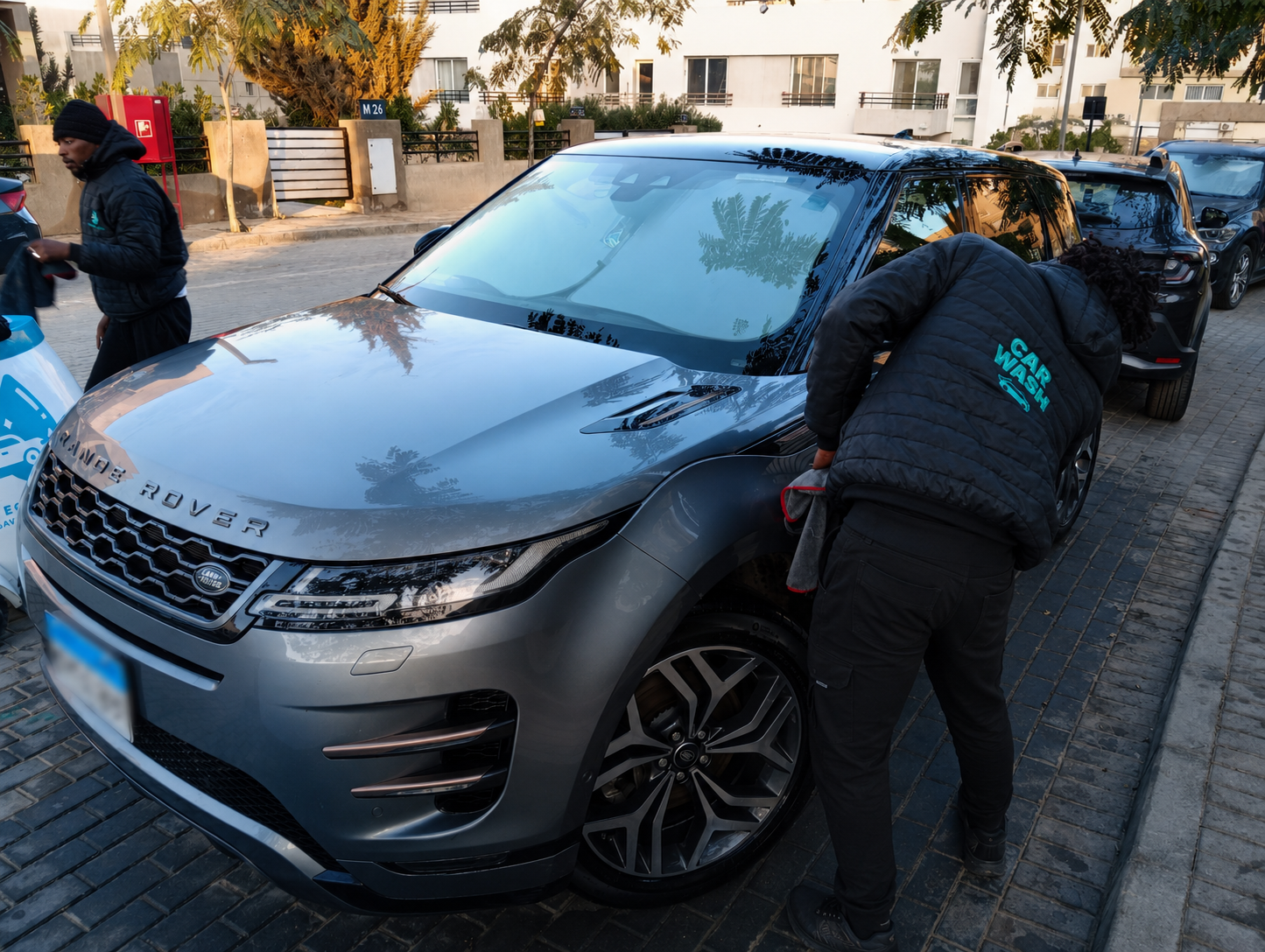 Equa Wash worker cleaning a Range Rover Evoque in an outdoor compound