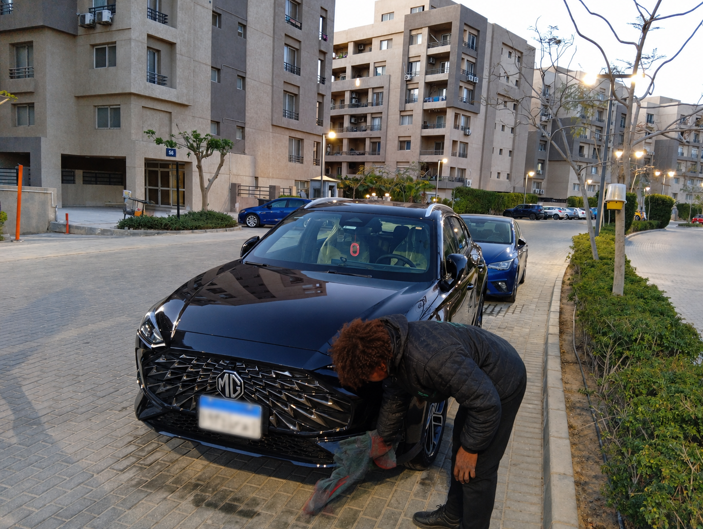 Equa Wash worker detailing an MG sedan at a residential compound