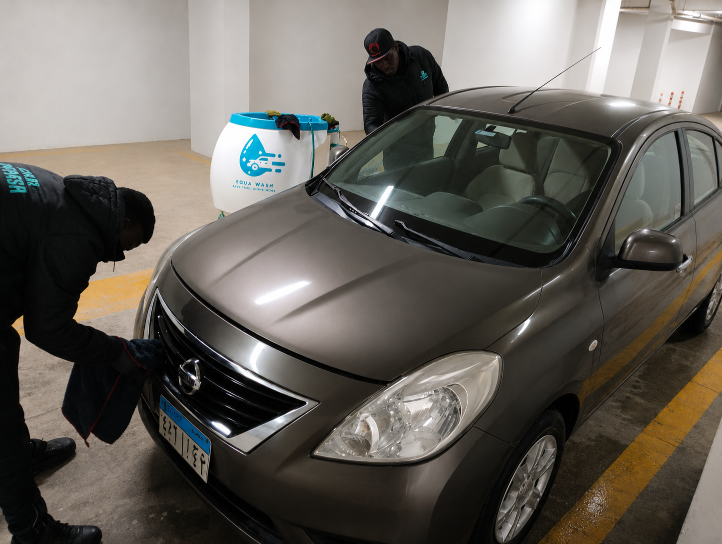 Two uniformed Equa Wash professionals servicing a sedan underground